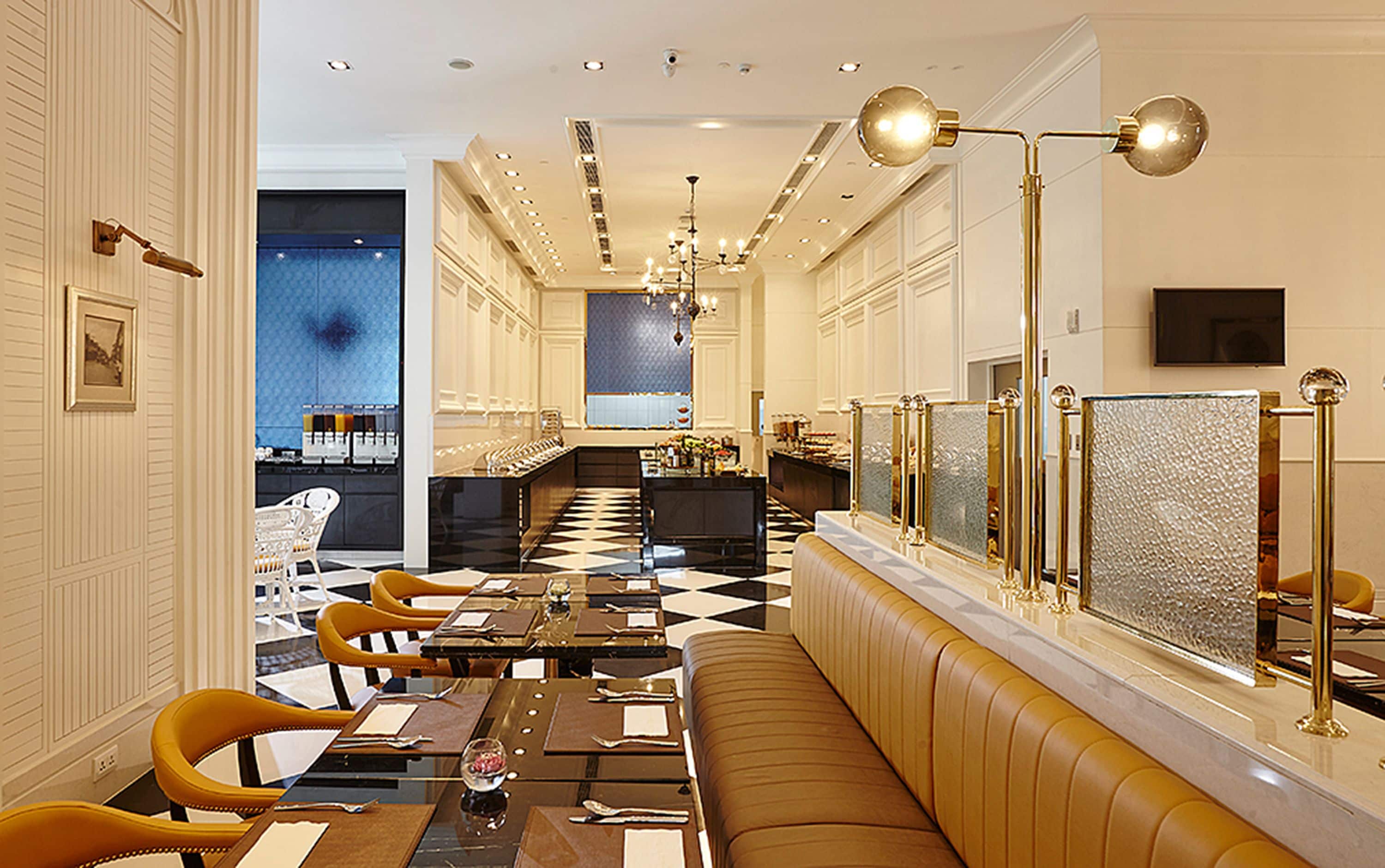 A hotel lobby with a checkered floor, a long counter, and a seating area with a sofa and chairs.