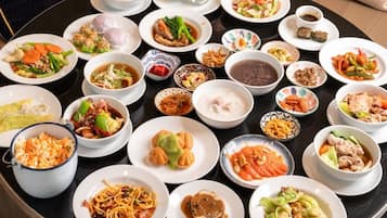 A table with various dishes, including noodles, dumplings, and soups.