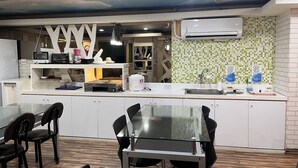 Une cuisine moderne avec une table et des chaises en verre, un four à micro-ondes encastré et un revêtement mural en carreaux.