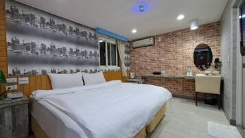 A bedroom with a bed, a cityscape mural, a brick wall, a mirror, and a small kitchenette.