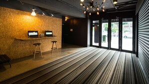 Un espace d’accueil avec un mur en bois, deux ordinateurs portables posés sur une étagère, un tabouret et une moquette à motifs.