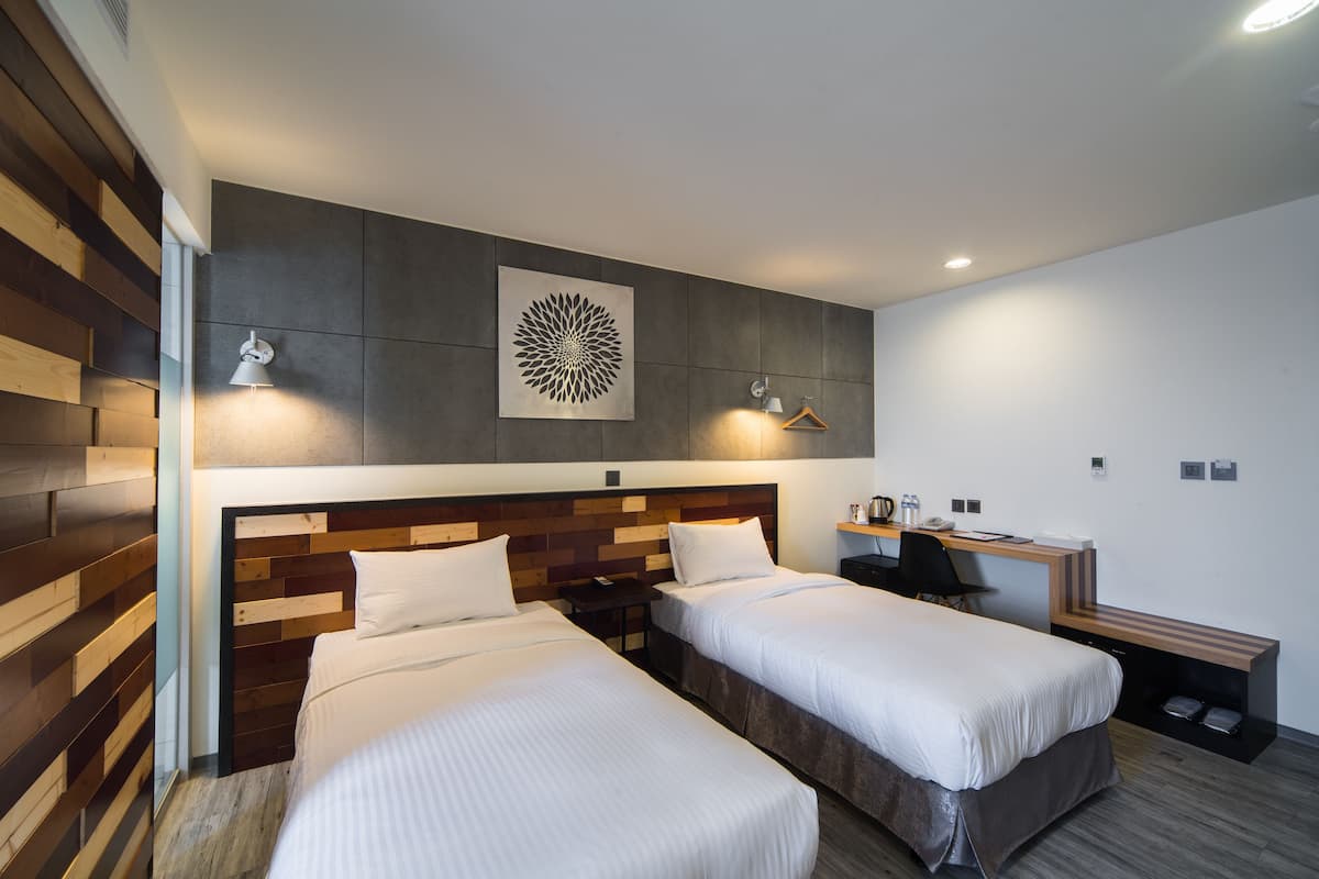 Une chambre d’hôtel moderne équipée de deux lits, d’un bureau et d’une œuvre d’art accrochée au mur.