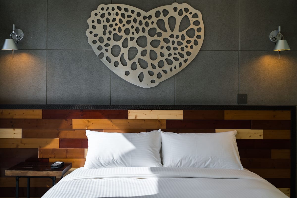 Une chambre à coucher avec une tête de lit en bois, un décor mural en forme de cœur et deux lampes de chevet.