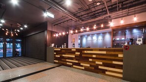 Un espace d’accueil avec un comptoir en bois, une porte à volets fermés et une vue sur la rue.