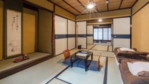 A traditional Japanese room with tatami flooring, a low table, a chair, and a bed. - Traditional Kyoto Home Bifuku Roujiya (Kyoto)