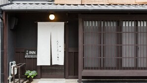 A traditional Japanese inn entrance with a signboard, a hanging banner, and a wooden gate. - Traditional Kyoto Home Bifuku Roujiya (Kyoto)
