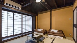 A traditional Japanese room with tatami flooring, a futon bed, a low table, and a large shoji screen window. - Traditional Kyoto Home Bifuku Roujiya (Kyoto)