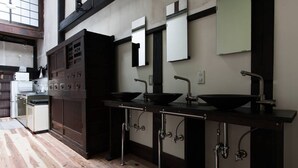 A kitchen with three black sinks, wooden cabinets, and a window overlooking the room.