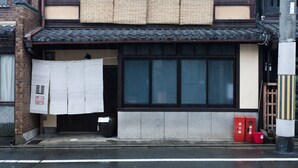 A traditional Japanese building with a tiled roof, large windows, and a small entrance.