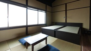 A traditional Japanese room with tatami flooring, a low wooden table, and a futon bed.