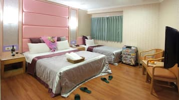 A hotel room with two beds, a TV, a desk, and slippers on the floor.