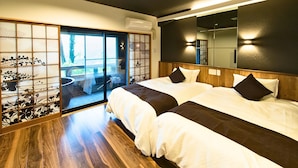 Habitación de hotel con dos camas, una puerta corrediza de vidrio que da a un balcón y un espejo grande en la pared.