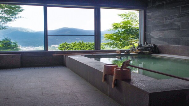 Un área de spa con un ventanal amplio, una pared de piedra y un banco de madera.