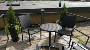 A wooden deck with two black wicker chairs and a small round table. - Forenom Aparthotel Raahe (Raahe)