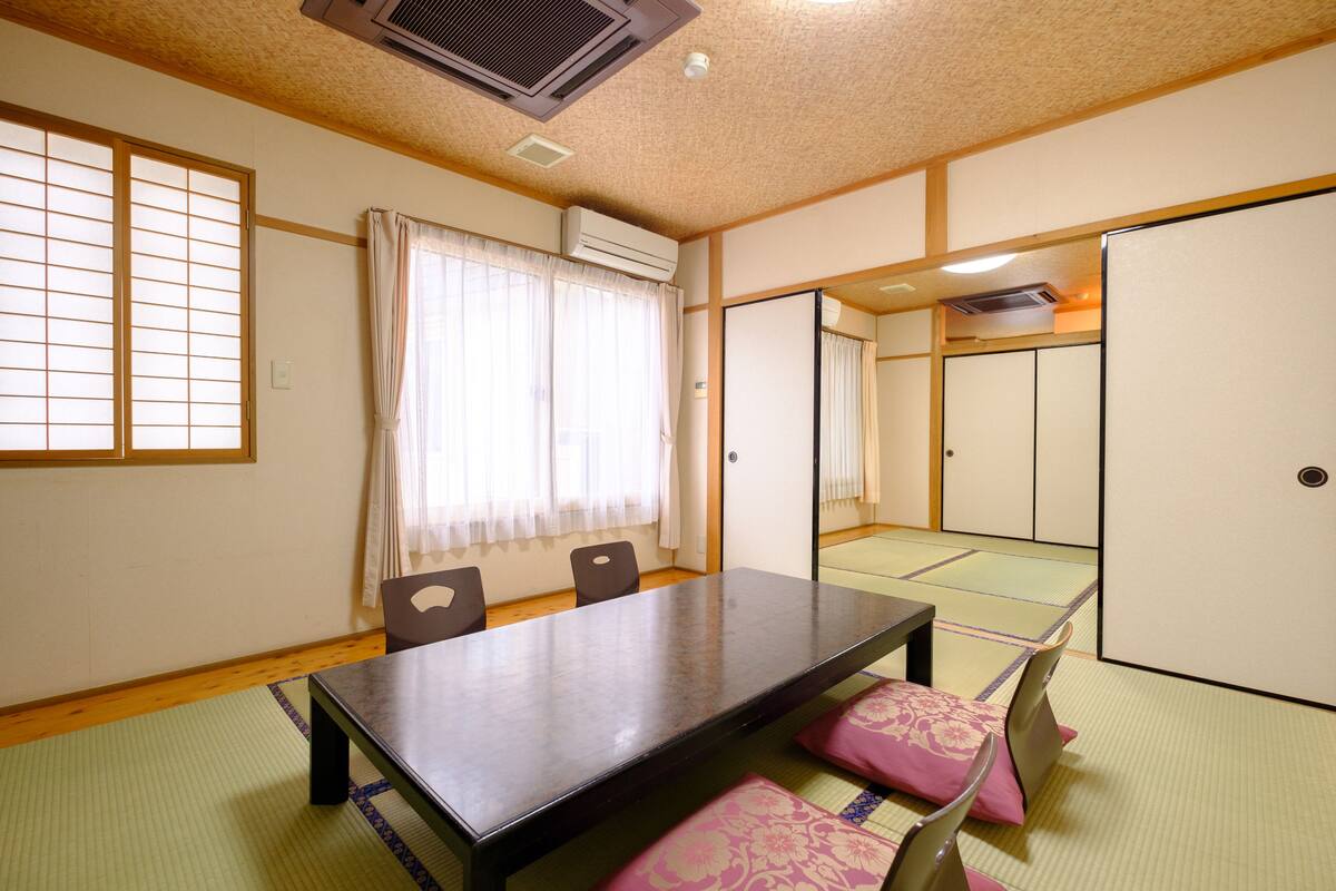 A traditional Japanese room with tatami flooring, a low table, and sliding doors.