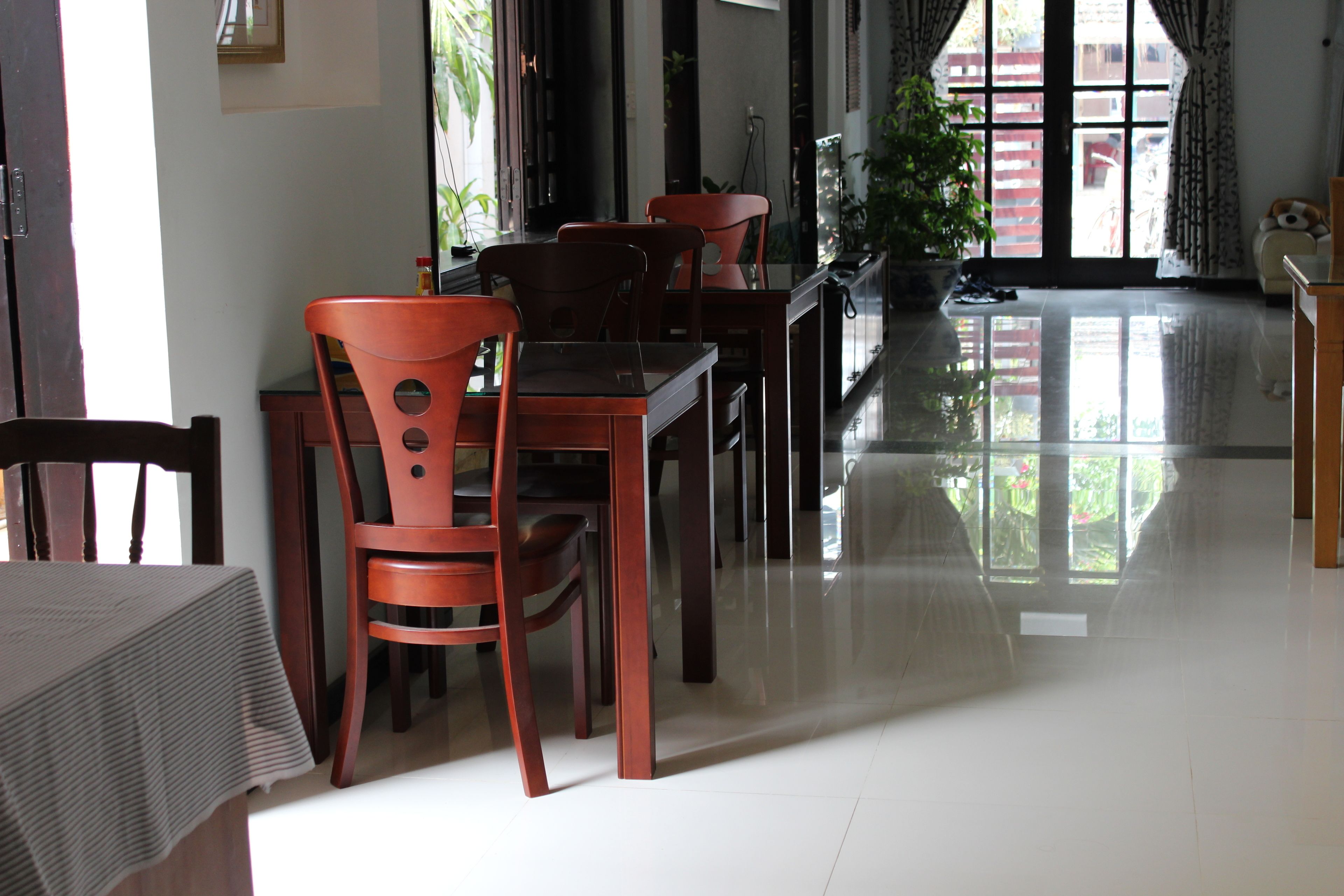 Un comedor con mobiliario de madera, una mesa de vidrio y vistas al exterior a través de amplios ventanales.