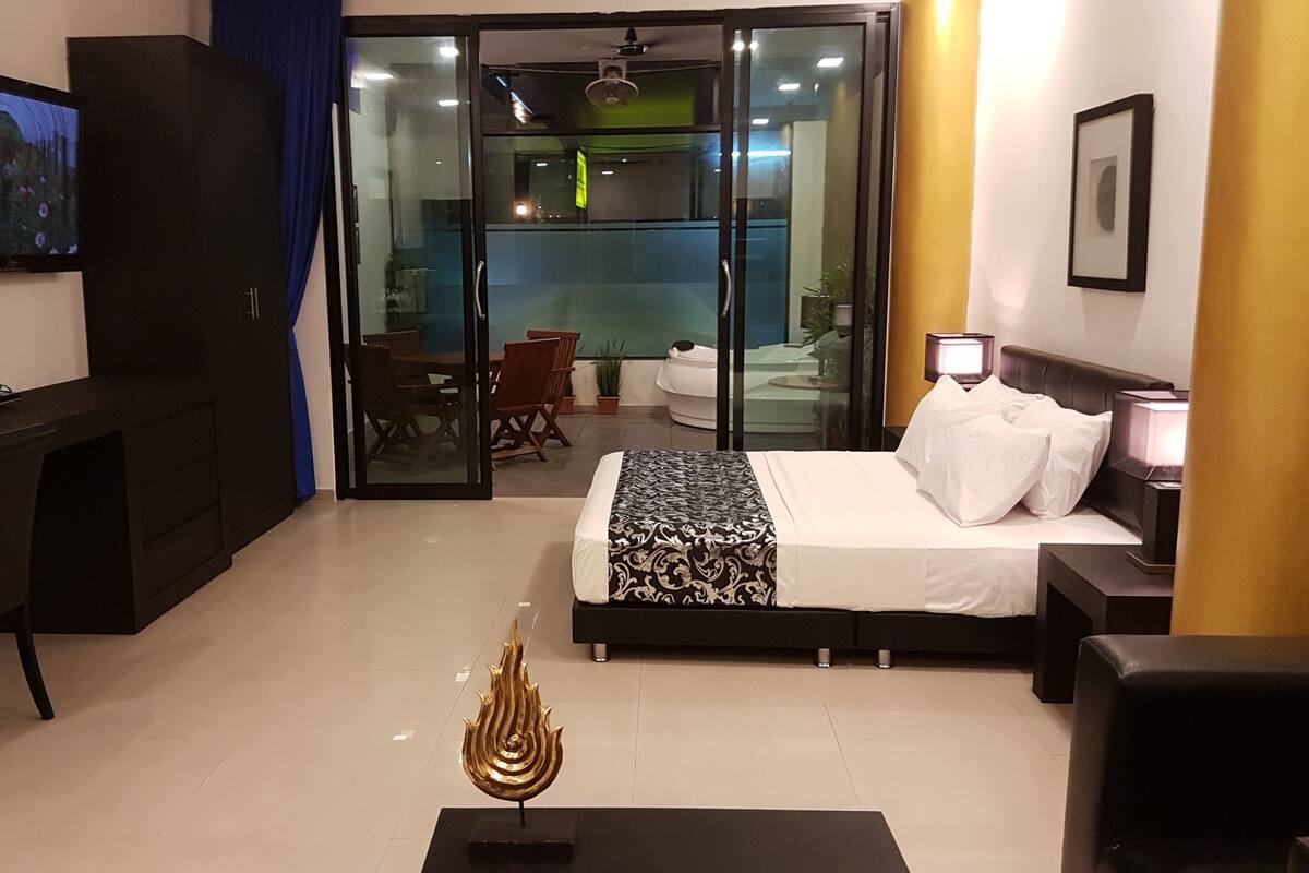 A modern hotel room with a bed, desk, and a sliding glass door leading to a balcony.