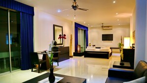 A modern hotel room with a dining area, a sofa, a bed, and a TV. - East Suites (Pattaya)