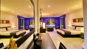 A mirrored hotel room with two beds, a dining table, and a view of the lobby. - East Suites (Pattaya)