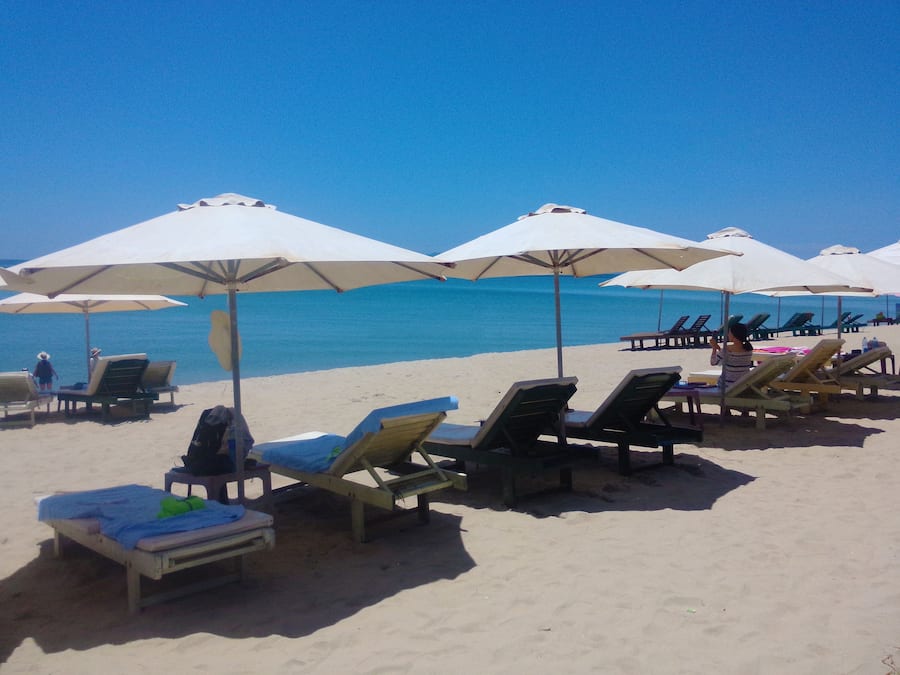 Praia particular, areia branca, espreguiçadeiras, guarda-sóis