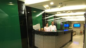 A reception area with a marble counter, a television mounted on the wall, and a sofa in the background. - Tong Bing Express (Hsinchu)