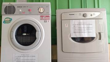 Two front-loading washing machines, one SANLUX and one Panasonic, with visible control panels and safety instructions.
