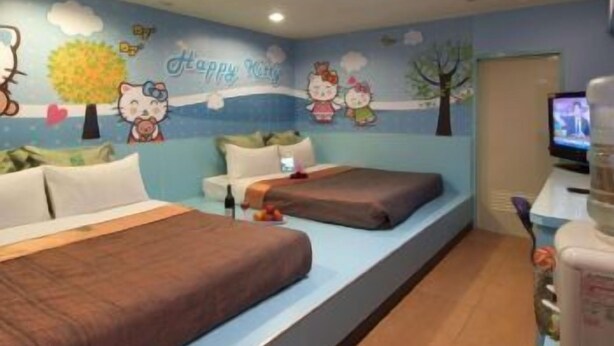 A children's room with two beds, a TV, and a wall decorated with cartoon characters and a 'Happy Kids' sign. - Tong Bing Express (Hsinchu)