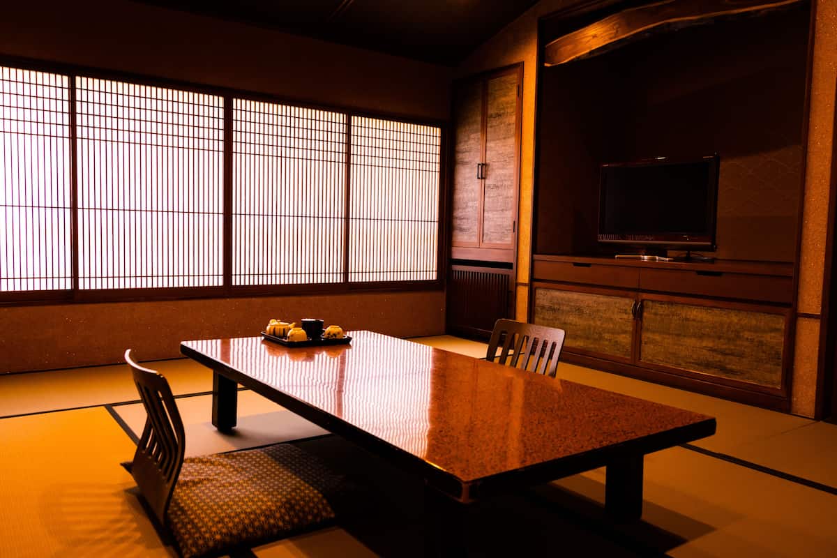 Une pièce de style japonais traditionnel, avec un sol recouvert de tatamis, une table basse, un téléviseur et des portes coulissantes.