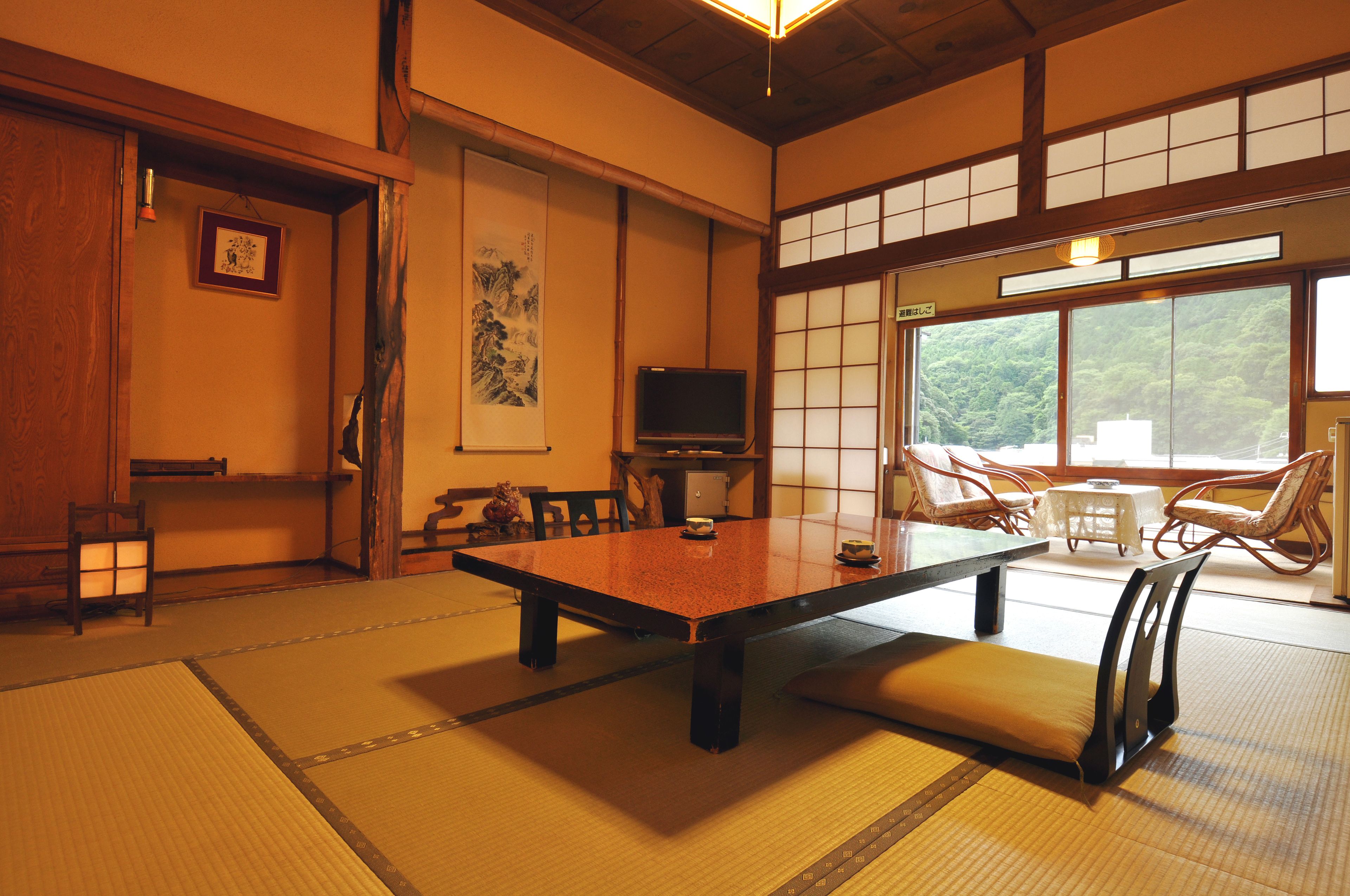 A traditional Japanese room with tatami flooring, a low table, and a television.