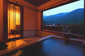Et traditionelt japansk rum med tatamimåtter, en skydedør og udsigt til et bjerrelandskab.
