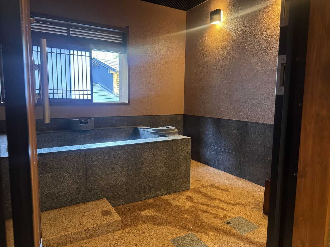 A bathroom with a stone sink, a window with bars, and a towel rack.
