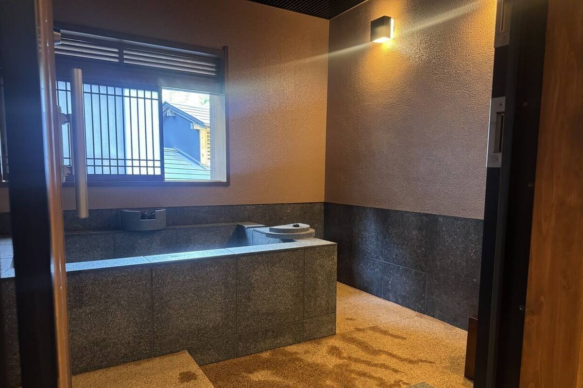 A bathroom with a stone sink, a window with bars, and a towel rack.