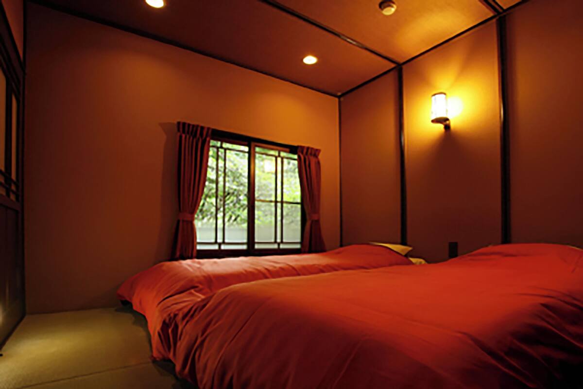 Une chambre avec deux lits, une fenêtre avec des rideaux, un luminaire fixé au mur et un plafonnier.