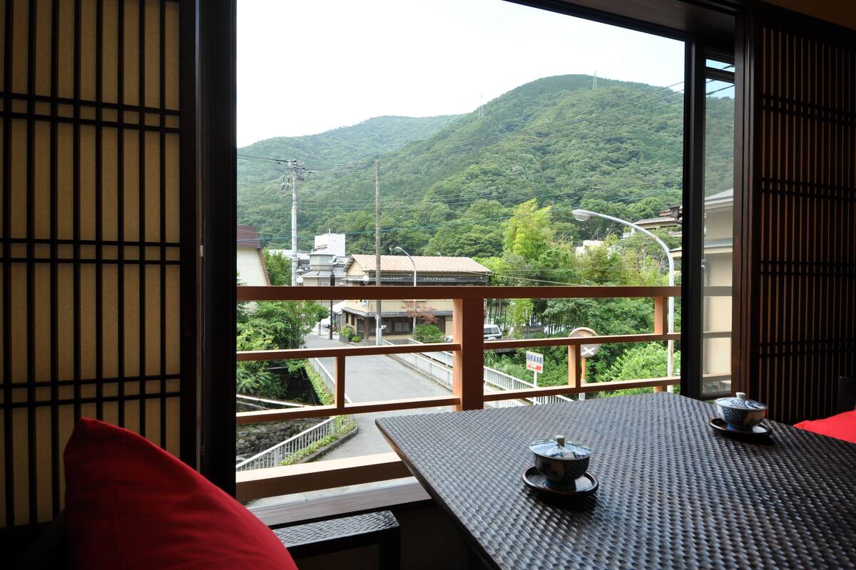 Une pièce avec vue sur une montagne, une table avec une théière et un coussin rouge.