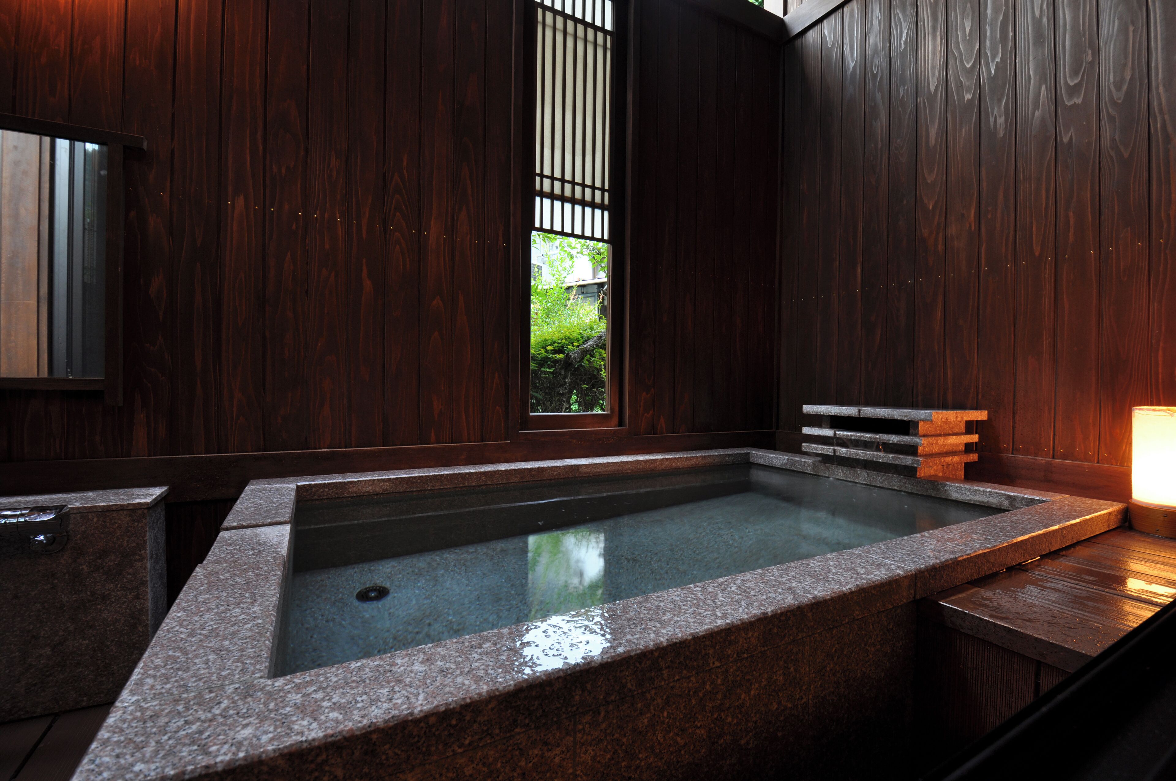 A spa area with a stone hot tub, wooden walls, and a small window.