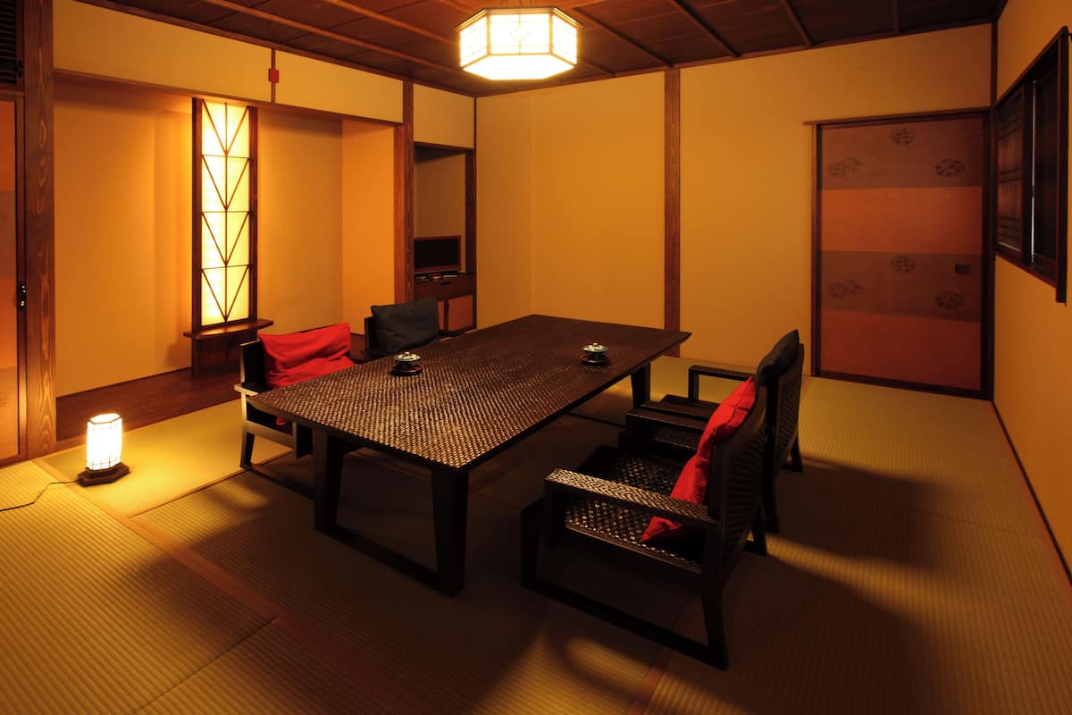 Une pièce de style japonais traditionnel, avec un sol recouvert de tatamis, une table basse et des paravents en papier.