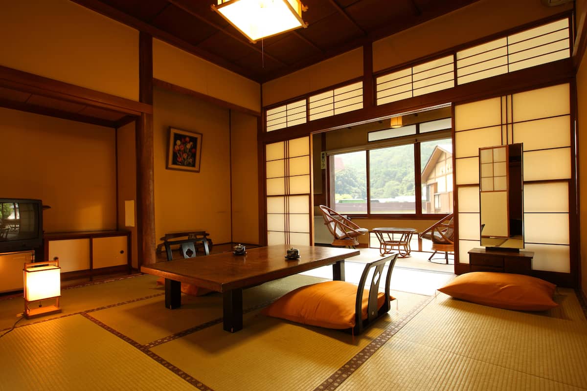 Une pièce de style japonais traditionnel, avec un sol recouvert de tatamis, une table basse, des coussins et des portes coulissantes.