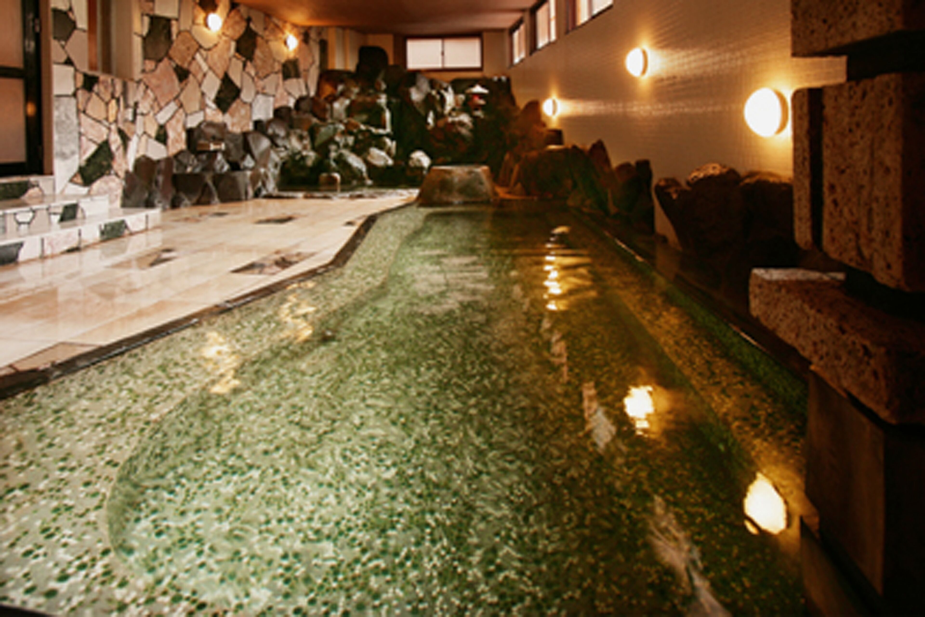 A pool with a stone wall and a stone ledge.
