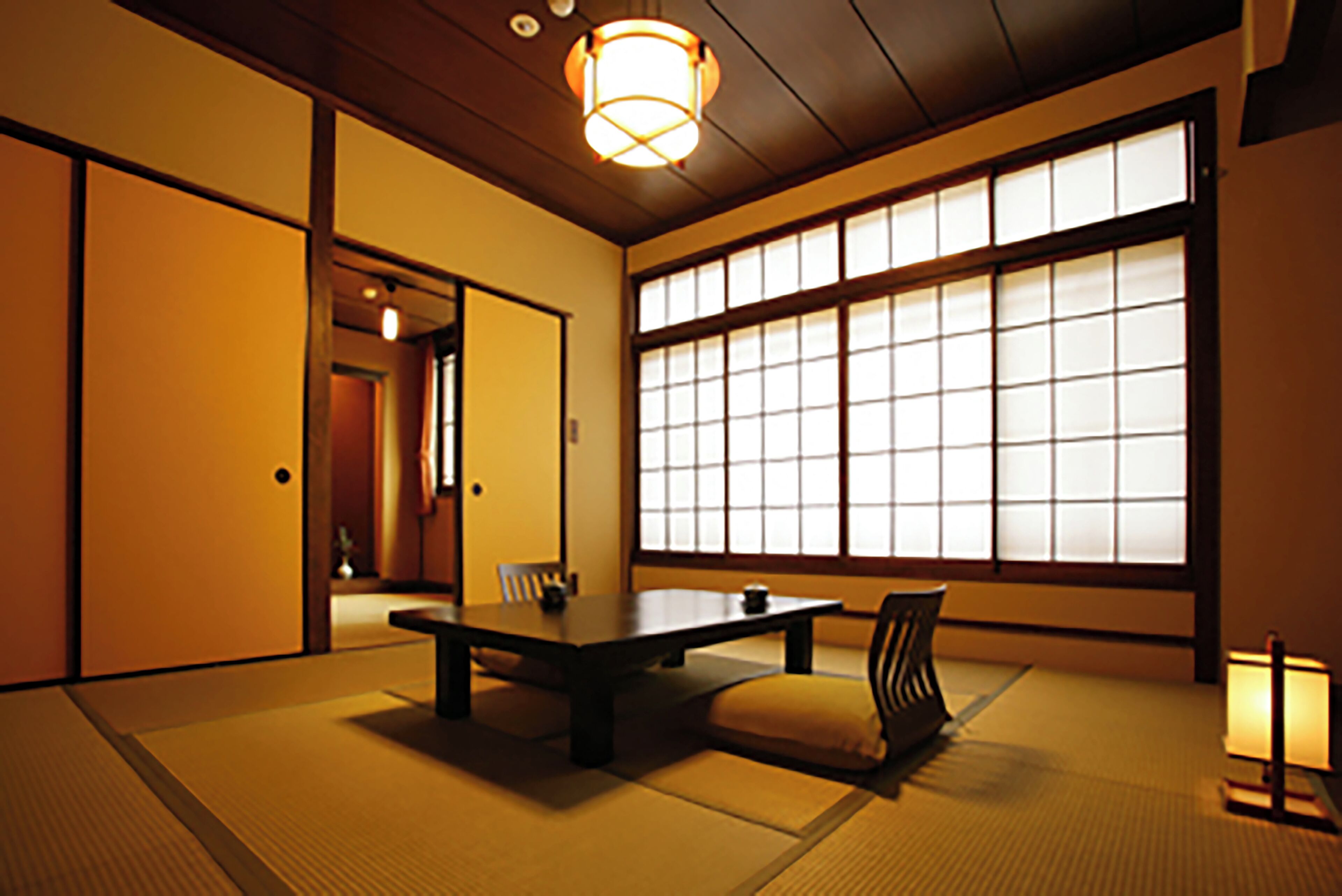 Une pièce de style japonais traditionnel, avec un sol recouvert de tatamis, une table basse et des portes coulissantes.