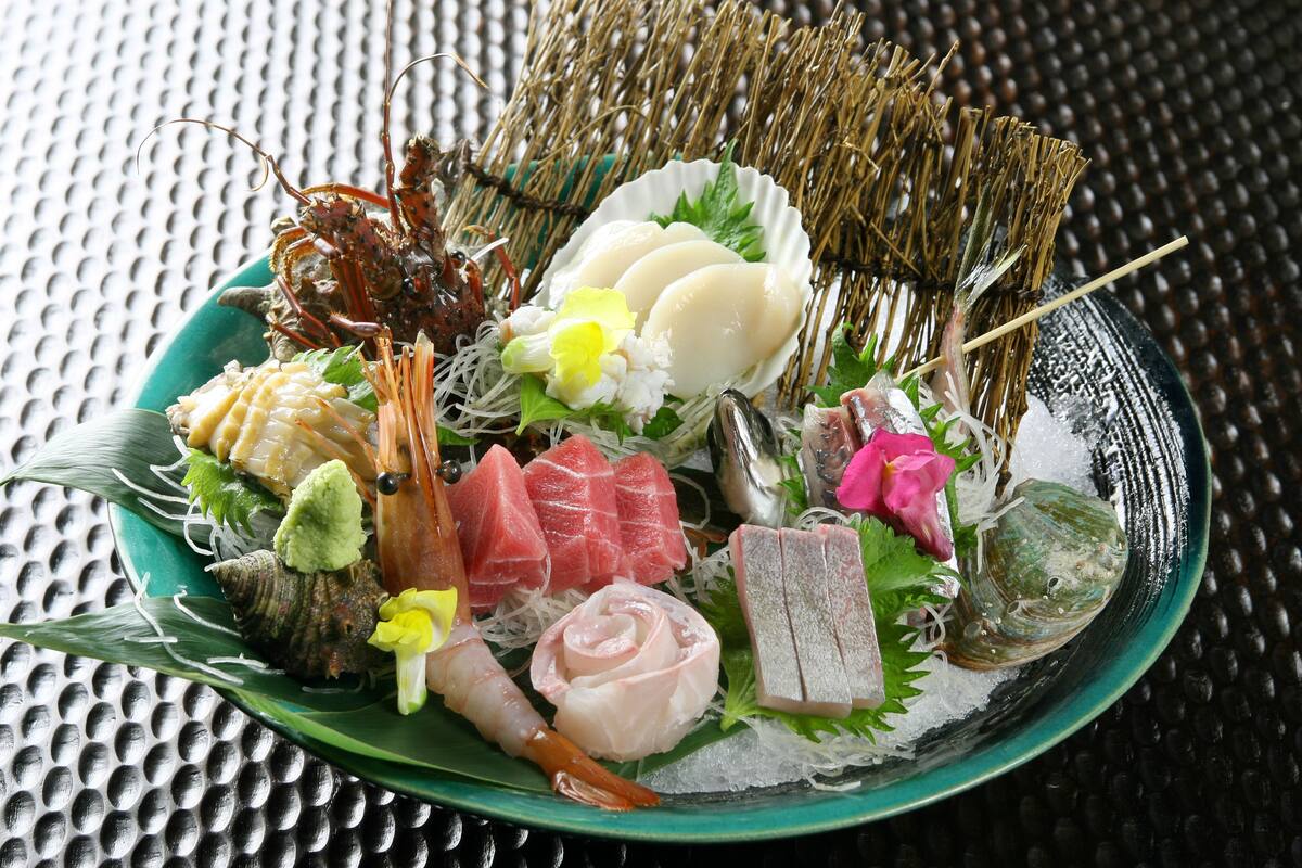 Une assiette de fruits de mer et de sushis variés, disposés sur une surface texturée.