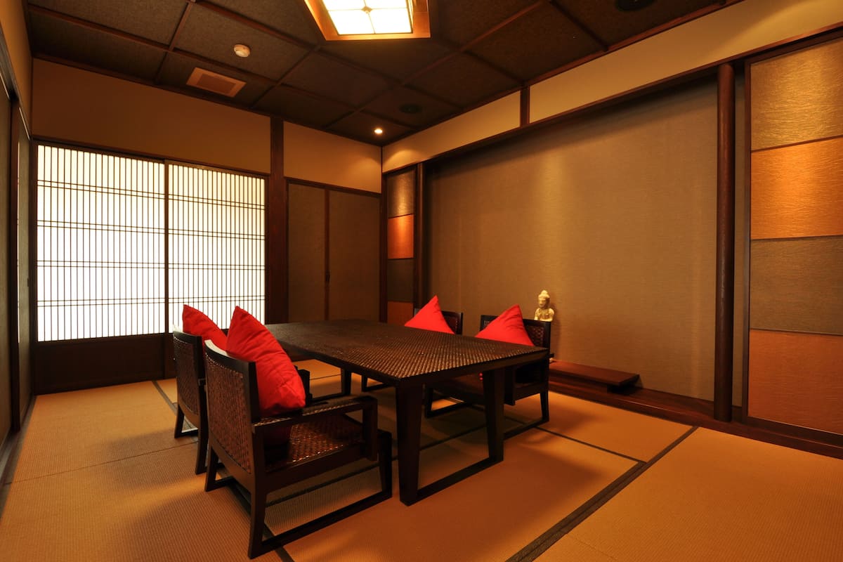 Une pièce de style japonais traditionnel, avec un sol recouvert de tatamis, une table basse et des coussins rouges.