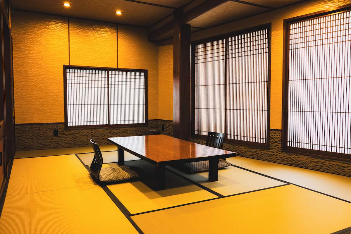 Une pièce de style japonais traditionnel, avec un sol recouvert de tatamis, une table basse et des portes coulissantes.