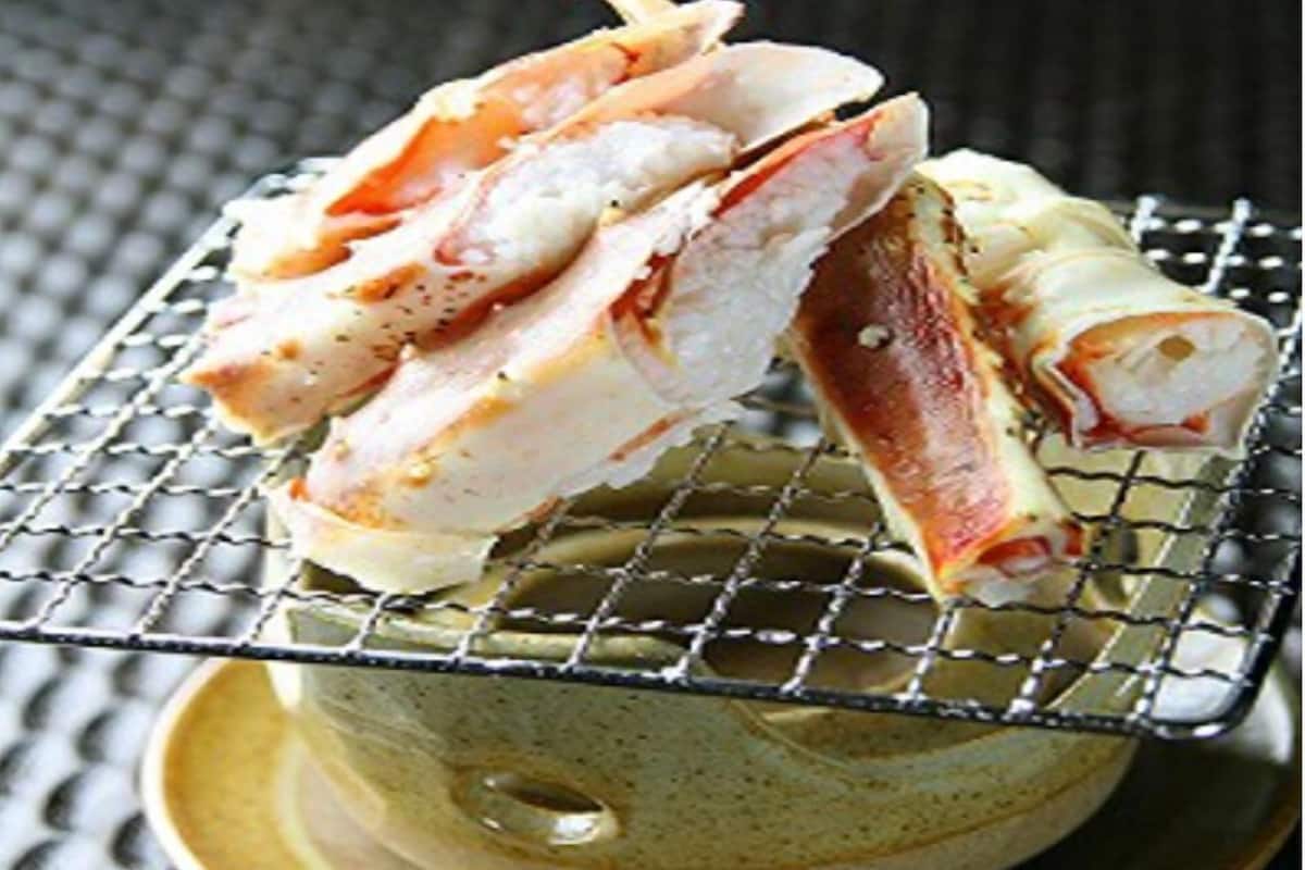 Un sandwich posé sur une grille métallique, lui-même placé sur une assiette en céramique.