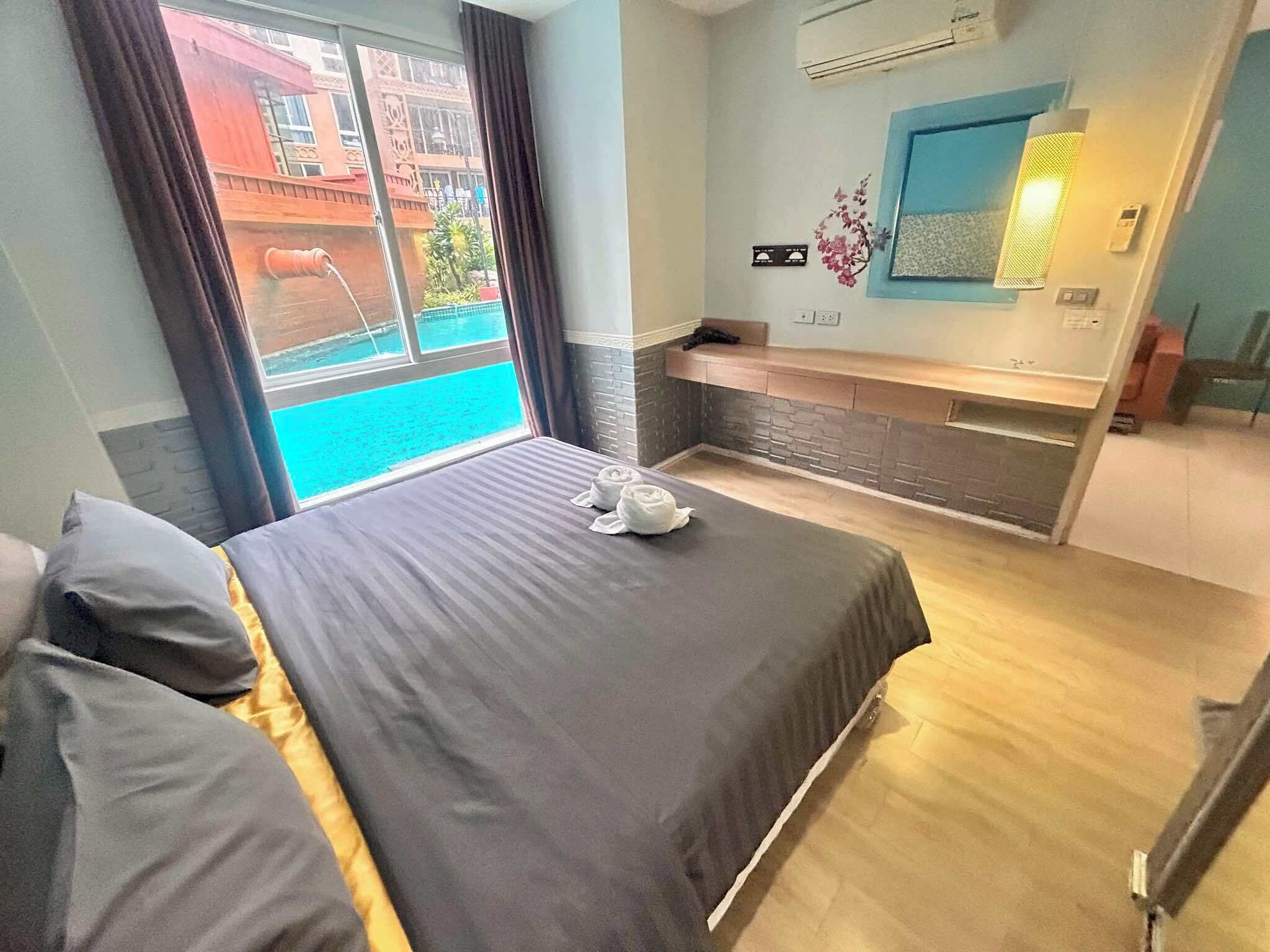 Ein Hotelzimmer mit Bett, kleinem Schreibtisch, einem Fenster mit Vorhängen und Blick nach draußen.