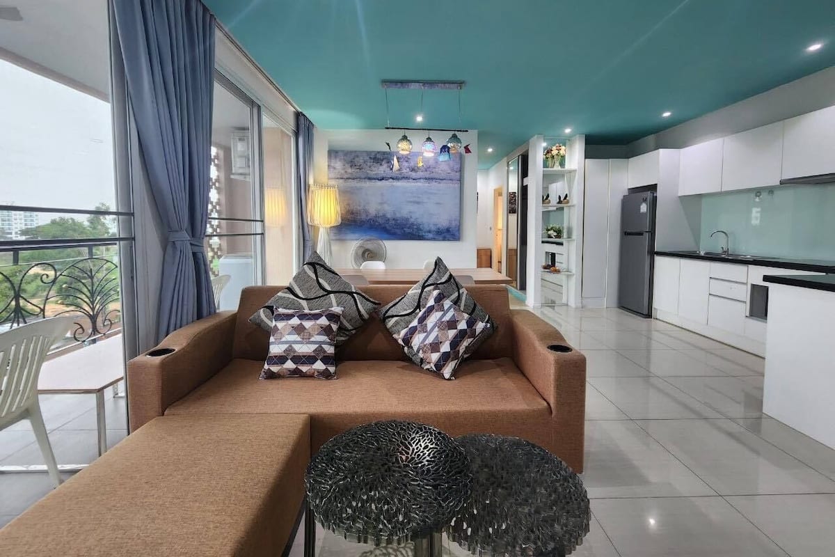 A modern living room with a sofa, patterned cushions, and a decorative glass table.