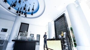 Un hall d’entrée moderne avec un comptoir d’accueil central, un grand élément décoratif bleu au plafond et un mur orné de motifs.