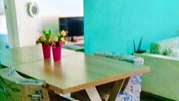 A dining area with a wooden table, clear chairs, and a teal-colored wall.