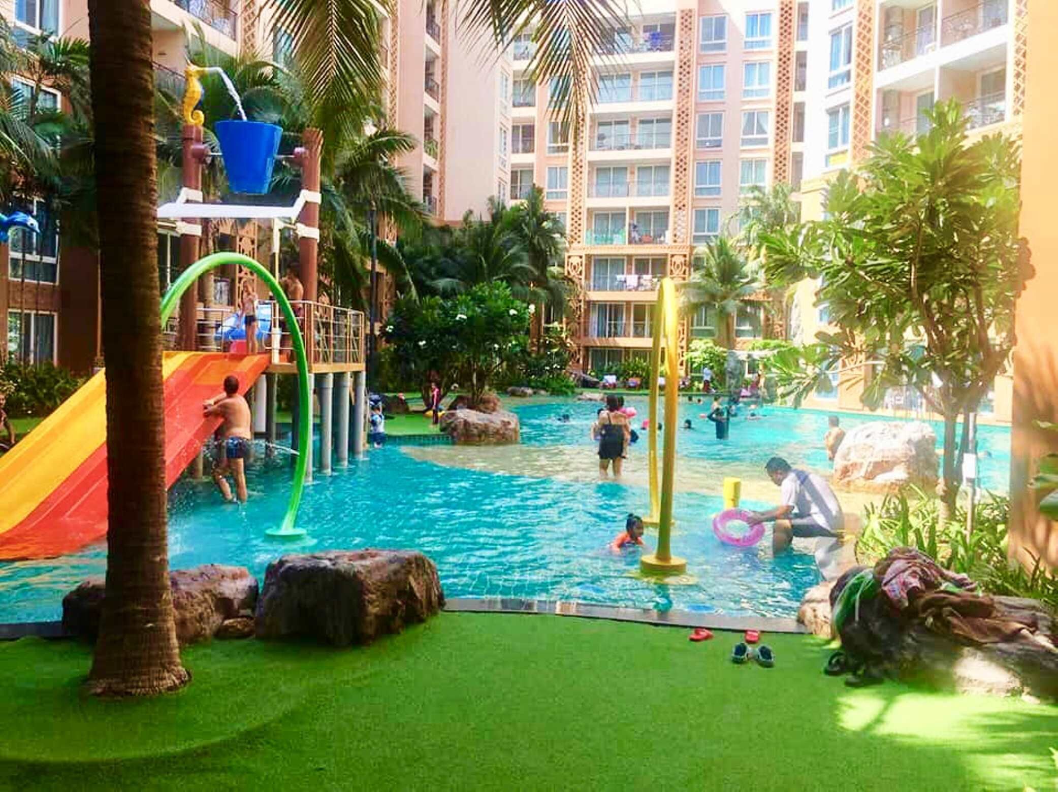 An indoor pool area with slides, water features, and palm trees.