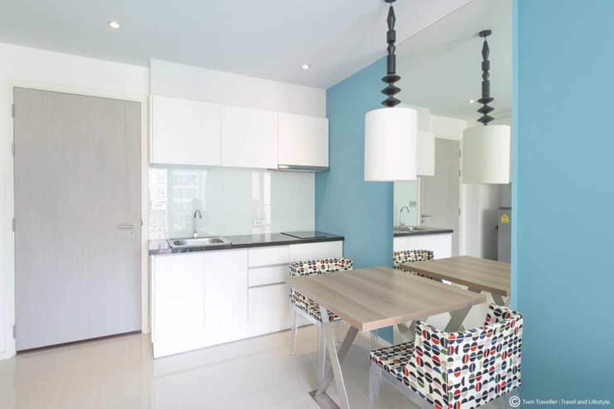 Una cocina moderna con armarios blancos, una mesa de comedor de madera y sillas estampadas.