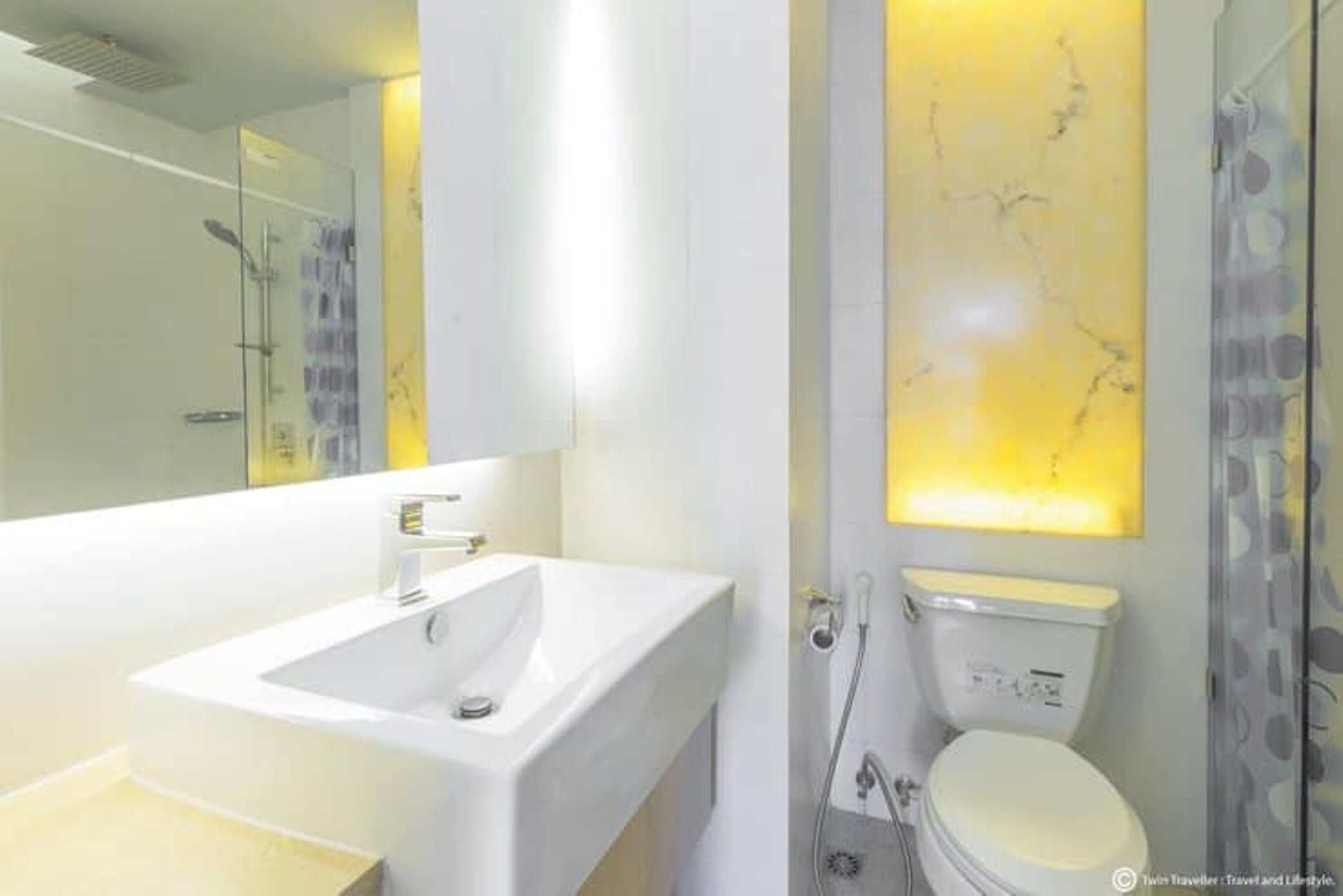 Een moderne badkamer met een wit wastafelmeubel, spiegel en toilet.